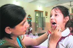 A doctor examines the teeth of a student during a medical camp organised by the Rotary Club in Jammu on Monday.