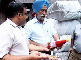 Civil Surgeon Chandanjit Singh Kaundal looks at a bottle of spurious sauce during a raid at a factory in Amritsar on Tuesday.