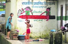 Two girls wash clothes at a primary school in Dehradun