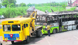A crane tows away a torched bus to clear the NH-10 at Mayyar village in Hisar