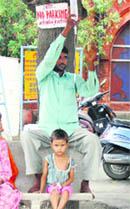 A man tends to his ailing child in the open due to the unavailability of beds at the trauma centre in Karnal