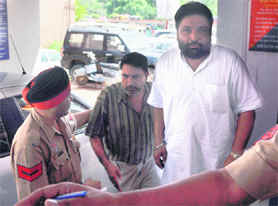 The prime accused in the Indira Awas Yojna scam, Lakshman Singh (in striped shirt) surrenders before the police in Ludhiana on Wednesday.
