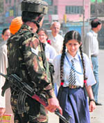 A student walks past an Army jawan on her way back home in Srinagar on Thursday. While all schools in the Valley remain closed due to the continuing curfew and shutdowns, students of Army Public School have been attending classes.