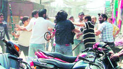 Two groups, carrying weapons, indulging in a fight, with a man training a pistol at a youth (encircled)