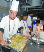 Chefs work at the kitchen of the Games Village in New Delhi 