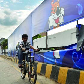 SHERA WOUNDED! A child cycles past near a damaged poster of the CWG mascot in New Delhi