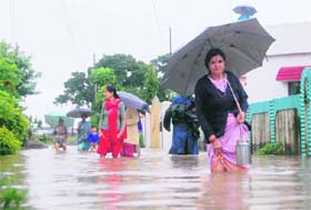 Women wade through water outside their homes in Dehradun