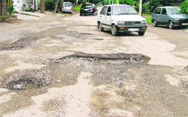 A potholed road at Phase I, Dugri, offers a bumpy ride to motorists