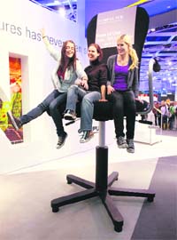 Visitors at the booth of Japanese camera maker Olympus pose for a happy snap on a giant office chair on the first day of the world's largest fair for imaging in Cologne
