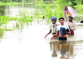 Residents of Raysi village in the Lakshar area wade through a submerged stretch