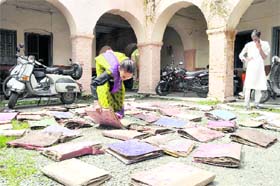 An employee of the Dehradun Municipal Corporation spreads out office records to dry in the sun