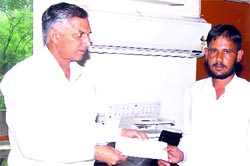 Deputy Commissioner Yudhvir Singh Khialiya hands over a cheque for Rs 10 lakh to Anil Kumar, brother of Mayyar police firing victim Sunil Kumar, at Hisar on Tuesday.