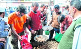 People buy vegetables from a vendor in the Hari Singh High Street in Srinagar on Tuesday.