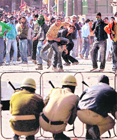 Security personnel try to protect themselves as protesters hurl stones at them in Srinagar.