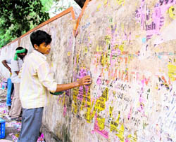 A JMC worker removes posters from a wall during a special drive in Jammu on Wednesday