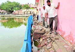 Residents pass through a broken path that collapsed due to waterlogging in Dadu Majra