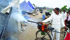 A domestic breeding controller fumigates the relief camps of the flood-affected victims near the Yamuna in Delhi