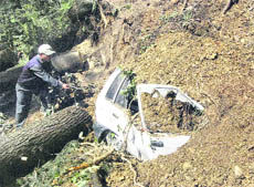 A man looks at a car which was buried after a landslide in Chhota Shimla on Friday