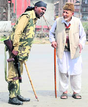 An old man seeks assistance from a CRPF jawan in a curfew-bound locality of Srinagar.