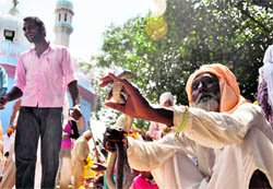 A snake charmer shows off his reptile to the crowd outside Guga Marhi at Chhapaar Mela on Friday