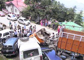 Onlookers gather near an accident spot where a truck rammed into parked vehicles, near Lakkar Bazaar Bus Stand, in Shimla