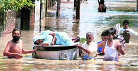 People carry a woman on an utensil as they shift to a safer place from a flooded colony at Vrindavan in Mathura (UP) on Saturday