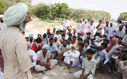 Protesting residents (left) of Kutti Kishanpura village squat on the road.