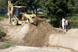 A JCB is engaged in building an earthen bundh on the Punjab-Haryana drain near Doomwali in the Bathinda district on Saturday. 