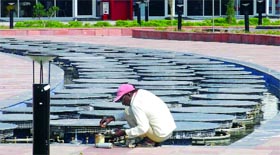 A worker repairs the musical fountain at CWG Village on Sunday.