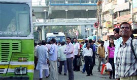 People wait for the bus at Laxmi Nagar in New Delhi on Sunday as Blueline buses are taken off road till the Games.