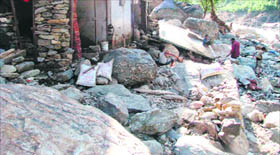 Villagers take stock of the damage caused by floods and landslides in Almora district.