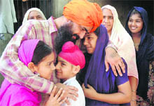 Truck driver Gurjant Singh hugs his children on returning home in Mauran village in Sangrur on Monday. 