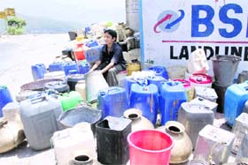A boy waits at a water standpost with empty containers in Tehri Garhwal