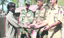 Hizbul Mujahideen militant Taj Mohammad hands over arms and ammunition to Army officers in Thannamandi in Rajouri on Wednesday.