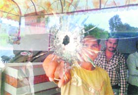An employee shows a bullet shot on a window in a restaurant at Dhakoli