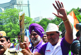 Sports veterans hold the Queen's Baton as it arrives in New Delhi on Thursday.