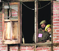Policemen keep vigil from the window of a house in Srinagar on Thursday. 