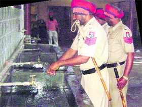 Policemen wash utensils after partaking langar at a religious place in Ahmedgarh on Thursday.
