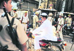 Paramilitary troops stand guard as a man rides past near a mosque in Ayodhya on Friday