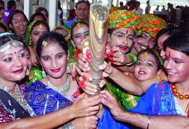 Schoolchildren and participants of a flag-hoisting ceremony at the Games Village hold the Queen's Baton during its relay in New Delhi on Saturday.