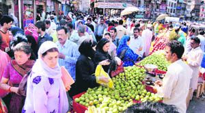 Women buy fruits at a market during relaxation in the curfew in Srinagar on Saturday.