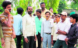 Migrant labourers attend phone calls of the relatives of those who died in shed collapse in Ludhiana on Friday