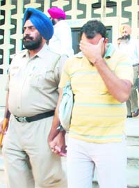 An accused hides his face after being arrested from an examination centre in Government Model Senior Secondary School, Sector 23, Chandigarh