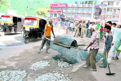 Labourers repair a damaged road in the main chowk ahead of the Navratras in Katra on Sunday