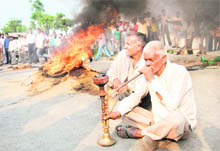  Unfazed, farmers smoke hookah after burning their paddy on the GT road in Karnal on Monday. 