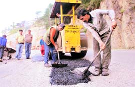 PWD workers repair a road at Sanjauli near Shimla on Monday. 