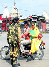 A CRPF man questions a couple in a curfew-bound area in Srinagar. Only government employees, schoolchildren and teachers are allowed to move during curfew