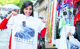 Miss World contestant Manasvi Mamgai of India shows a T-shirt she bought after visiting the Mutianyu Great Wall in Beijing on Tuesday. Contestants from 120 countries will compete in the 60th Miss World Final to be held on Sanya Island October 30.