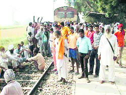 Protesting farmers sit on the railway line in Dod village in Ferozepur district on Thursday.
