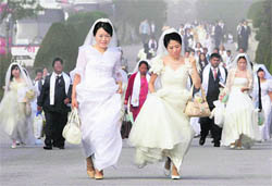 Brides rush to participate in a mass wedding ceremony in Ansan, South Korea, on Sunday. Some 7,200 South Korean and foreign couples exchanged or reaffirmed marriage vows in the Unification Church's second mass wedding this year